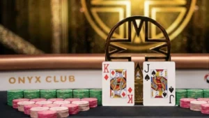 Jean-Robert Bellande smiling at the poker table with the Onyx High Roller trophy, chips, and his winning King of Diamonds and Jack of Spades hand.