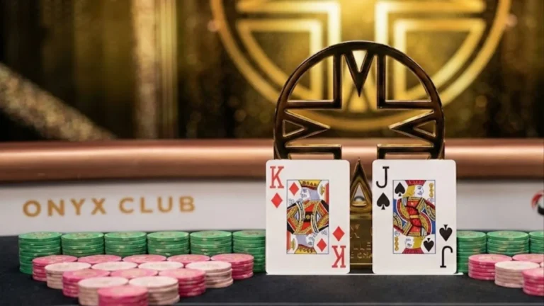 Jean-Robert Bellande smiling at the poker table with the Onyx High Roller trophy, chips, and his winning King of Diamonds and Jack of Spades hand.